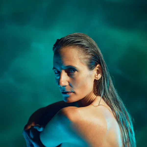 Kvinde med bar overkrop og langt vådt hår på grøn baggrund. Fra teaterforestillingen Fruen fra havet på Odense Teater